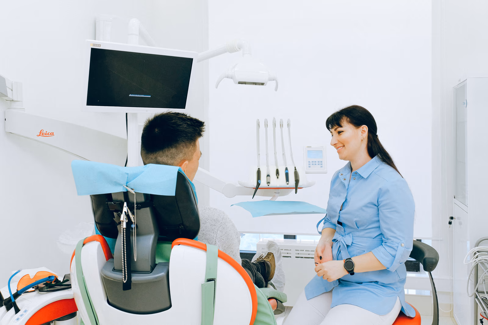A dentist talking with a patient in a bright office