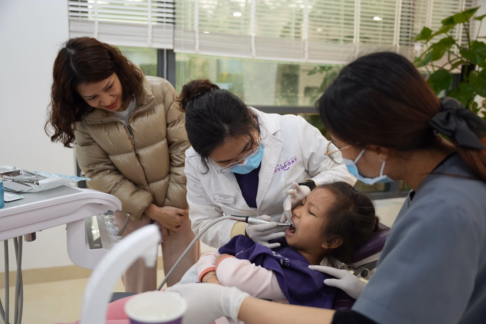 A dentist examining a child's teeth with a parent present